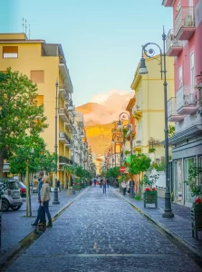 Sidewalk cuts through strip of yellow and pink building with mountain in the background