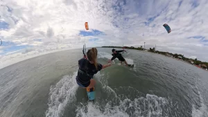 Two people highfive while kiteboarding on open water